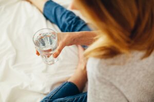 woman holding glass of water while in bed